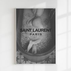 a black and white photo of a baby's feet in a bathtub with the words saint laurent paris on it