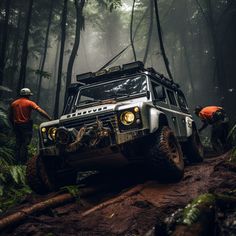 two men are working on a jeep in the middle of a forest with lots of trees