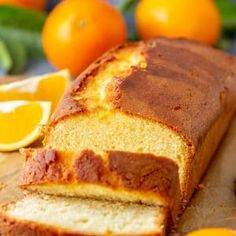 a loaf of orange bread sitting on top of a cutting board next to sliced oranges