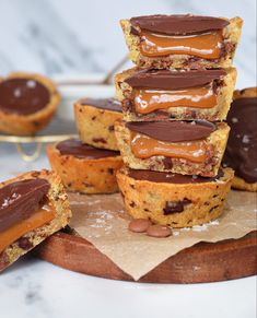 a stack of chocolate covered cookies on top of a cutting board next to other desserts