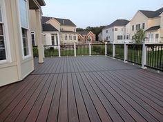 a wooden deck with white railings and black iron fence around the house's front yard