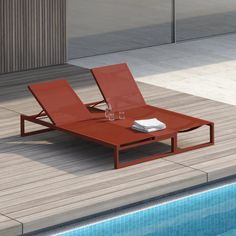 an orange lounge chair sitting next to a swimming pool with a glass of wine on it