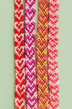 three different colored knitted bracelets on a green surface