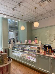 the inside of a bakery with lots of food on display and lights hanging from the ceiling