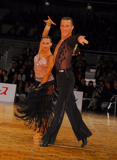 two people dancing on a wooden floor in front of an audience