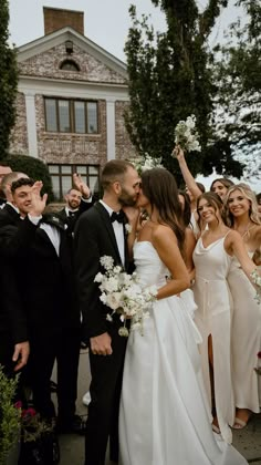 a group of people standing next to each other in front of a building with flowers