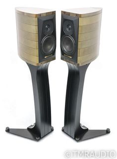 two black speakers sitting side by side on top of each other with gold trimmings