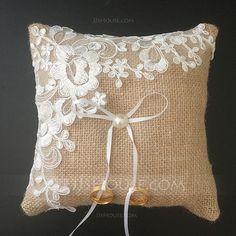 a decorative pillow with white lace and bells tied to the side on a white background