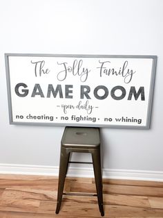 a game room sign sitting on top of a wooden stool in front of a white wall