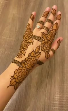 a woman's hand with henna on it and flowers painted on the palm