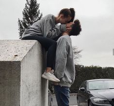 a man and woman kissing on the side of a road