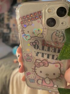 someone holding up their phone case with hello kitty stickers on the front and back