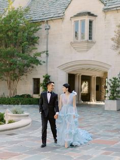 a man and woman are standing in front of a large building with a stone walkway