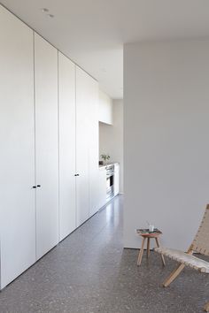 a chair sitting in the middle of a room next to a wall with white cupboards