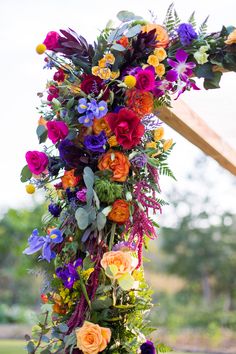 an arrangement of colorful flowers hanging from a cross