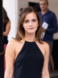 a woman in a black dress is posing for the camera with her hand on her hip