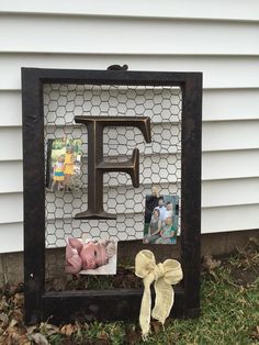 a photo frame with the letter f on it and photos pinned to it in front of a house