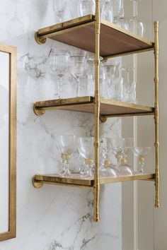 the shelves are filled with wine glasses and gold rimmed glasses on marble countertops