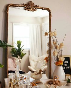 a mirror sitting on top of a table next to a vase filled with flowers and other items