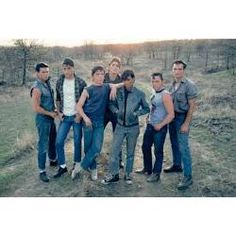 a group of young men standing next to each other on a dirt road in the woods