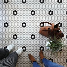 a woman's feet and purse on a tiled floor with black and white tiles