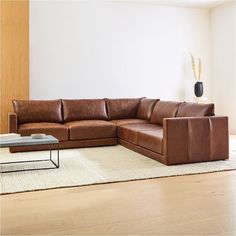 a brown leather couch sitting on top of a wooden floor next to a coffee table