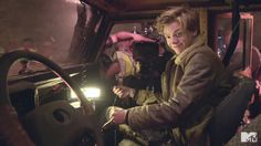 a woman sitting in the driver's seat of a truck with her hand on the steering wheel