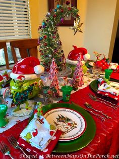 the table is set for christmas dinner with santa hats on it and plates, silverware