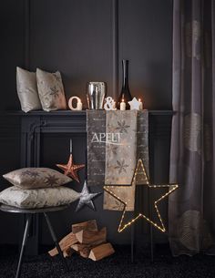 a black room with candles, pillows and decorative items on the floor next to a fireplace