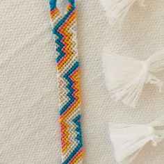 a close up of a beaded bracelet on a white surface with tassels