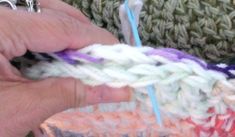 someone crocheting the ends of their hand made item with yarn and cottons