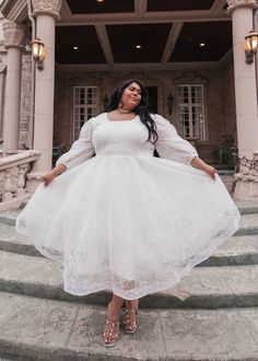 a woman in a white dress standing on some steps