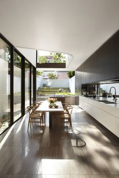 an open kitchen and dining room area with wooden flooring, white walls and ceiling