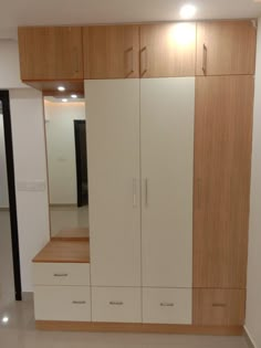 an empty room with wooden cabinets and white cupboards on the wall, in front of a doorway