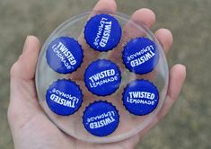 a person holding a glass ball with blue candies in it that say twisted lemonade