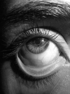 black and white photograph of an eye looking at something in the distance with long eyelashes