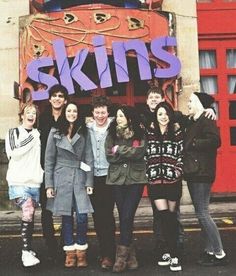 black and white photograph of young people standing in front of a building with the words skis on it