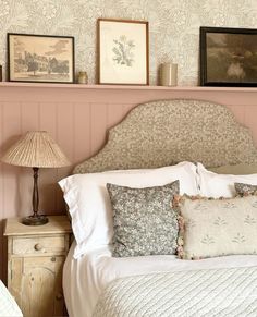 there is a bed with pillows on it and pictures above the headboard in this bedroom