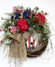 a patriotic wreath with red, white and blue flowers on the front is hung on a wall