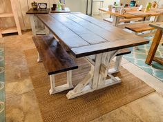 a kitchen table with two benches in front of it and an area rug on the floor