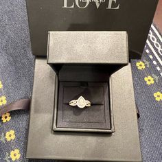 an engagement ring in a black box on a blue patterned cloth with the word love written across it