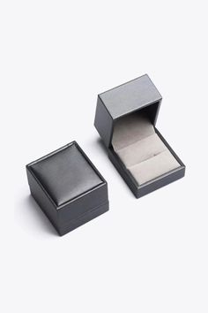 an open black box with a ring inside on a white surface, next to it's lid