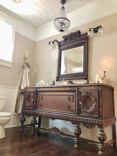 a bathroom with a vanity, toilet and chandelier