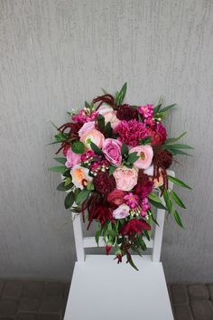 a bouquet of flowers sitting on top of a white chair in front of a wall