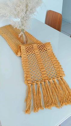 a crocheted yellow scarf with tassels sits on a dining room table