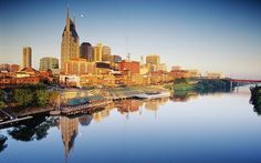 the city skyline is reflected in the still water of the river that runs through it