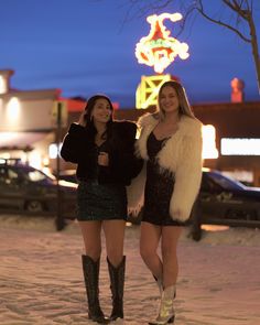 two beautiful women standing next to each other in the snow