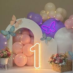 a birthday party with balloons, flowers and butterflies on the wall next to a number one sign