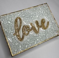 a close up of a piece of art with the word love spelled in gold