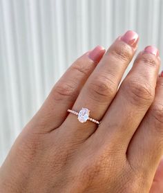 a woman's hand with a diamond ring on top of her finger and the other hand holding an engagement ring